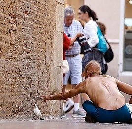 A man sitting on the ground on Calle Francisco de Rioja in Malaga.