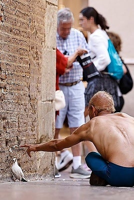A man sitting on the ground on Calle Francisco de Rioja in Malaga.