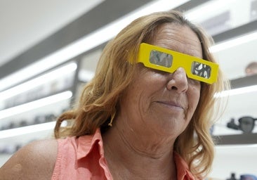 A customer at an optician's trying on glasses suitable for watching the eclipse.