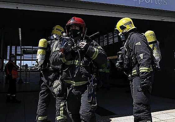 Firefighters rescue a person trapped in an overturned car following an accident in Churriana