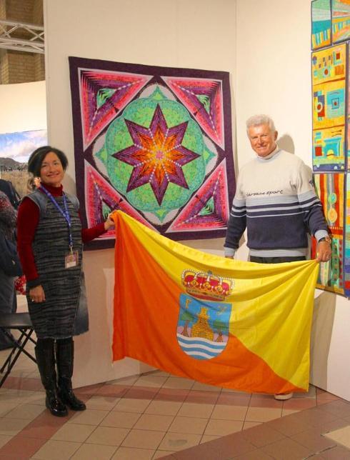 Oksana Mader and her husband with the award winning Kaleidoscope of Life and Love quilt.