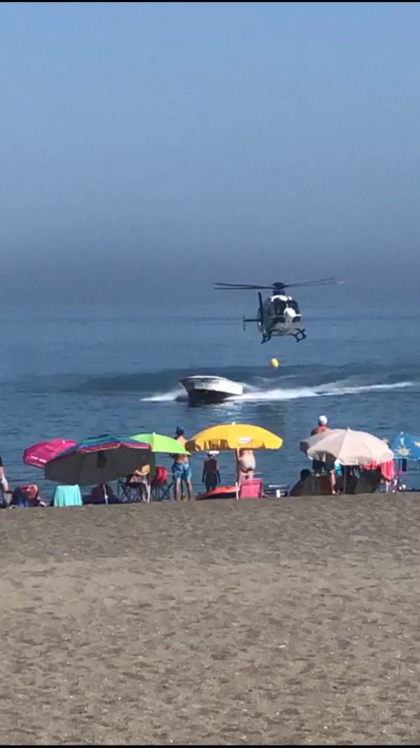 Bathers watch on as the helicopter pursues the speedboat just metres from the beach in Sabinillas, Manilva.