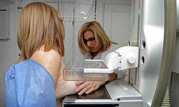 A specialist performs a breast examination on a patient.
