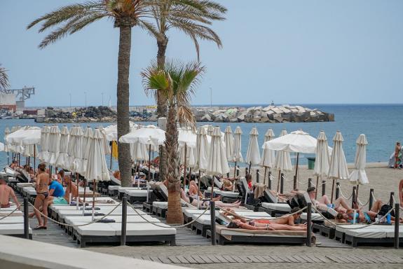 Tourists enjoying a reserved sunbed area in Marbella.