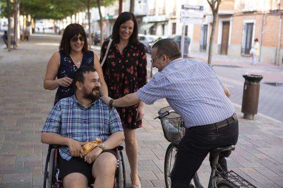 Amores, accompanied by  two councillors, is greeted  by a local resident.