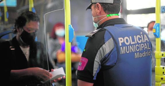 A Local Police officer checks on bus passengers in a controlled area of the capital this week.