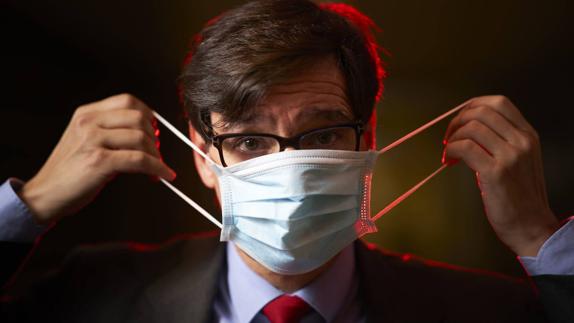 Health minister Salvador Illa puts on a mask.