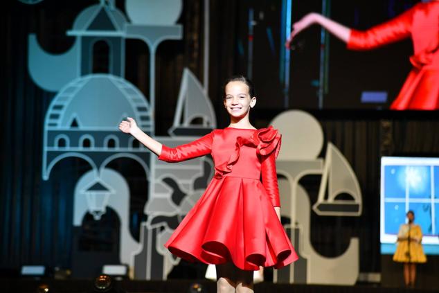 Una de las candidatas infantiles saluda a los foguerers y barraquers durante el desfile individual