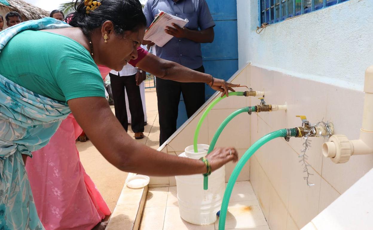 Una mujer india recogiendo agua en garrafas
