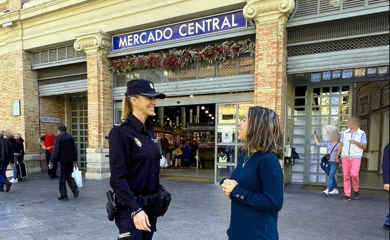 Una agente de la Policía Nacional hablando con una ciudadana frente al Mercado Central