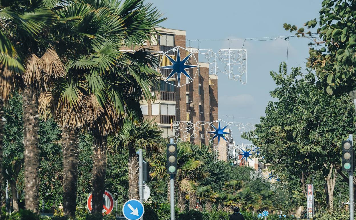 Una moto pasa por una calle de Alicante con las luces de Navidad