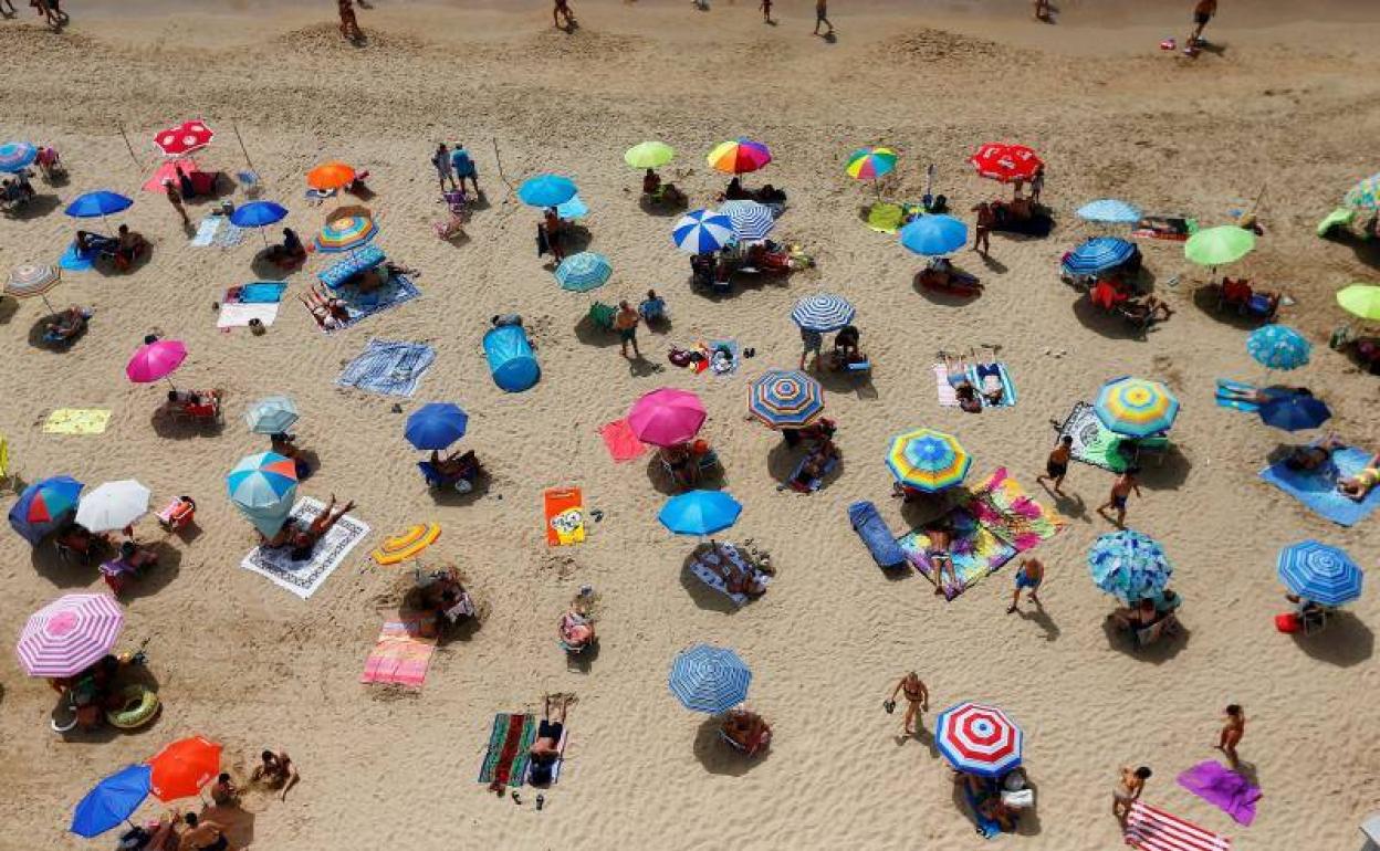 Decenas de turistas disfrutan del sol y la playa en Benidorm. 