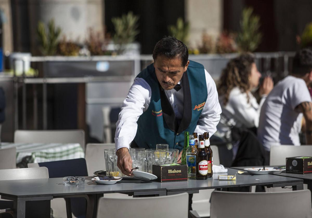 Un camarero limpia la mesa de una terraza