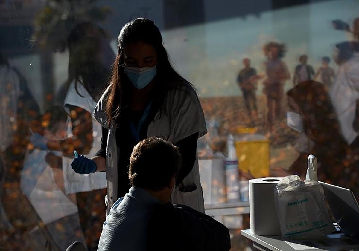 Una profesional sanitaria vacuna a una mujer.