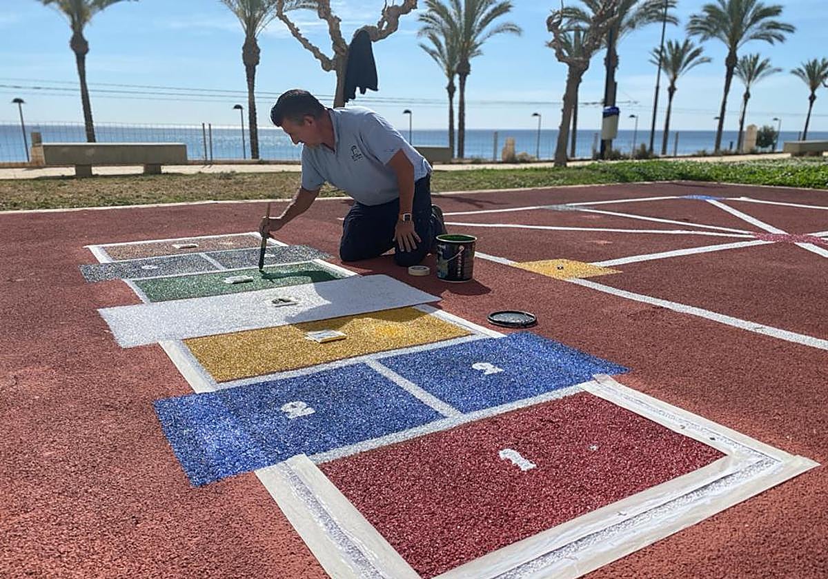 Un operario ultima el pintado de juegos tradicionales en El Campello.