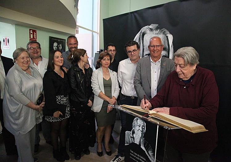 Imagen principal - Paco Muñoz firmando en el libro de honor y recibiendo la insignia de oro del Ayuntamiento.