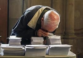 Una persoma observa con una lupa las papeletas de los diferentes partidos que concurren a las elecciones.