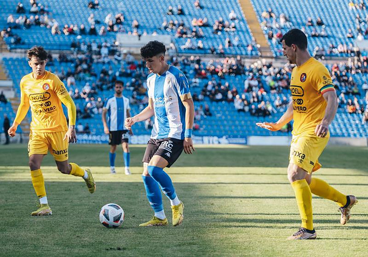 El extremo blanquiazul Luque, entre dos jugadores del Olot