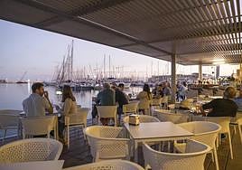 Turistas disfrutan durante una tarde en una terraza del puerto de Alicante
