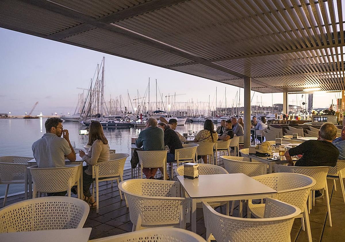 Turistas disfrutan durante una tarde en una terraza del puerto de Alicante