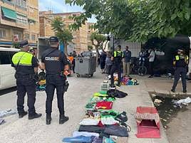 Los agentes, con la ropa decomisada.