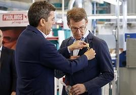 Carlos Mazón pone un prendido con una palma blanca a Feijóo, durante la visita del presidente popular a la fábrica de Pikolinos en Elche.