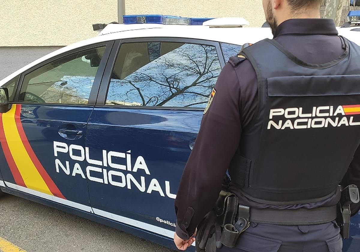 Agente de Policía Nacional con un coche patrulla.