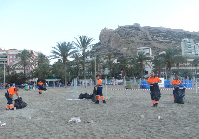 Operarios limpian las playas durante las Hogueras.