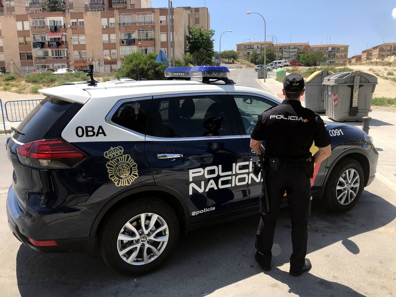 Imagen de un coche patrulla y un agente de la Policía Nacional.