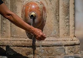 Un hombre se refresca la muñeca en una fuente.