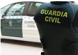 Agente de la Guardia Civil, junto a un coche patrulla.