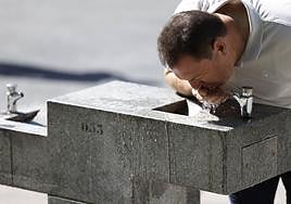 Un ciudadano bebe de una fuente ante el intenso calor.