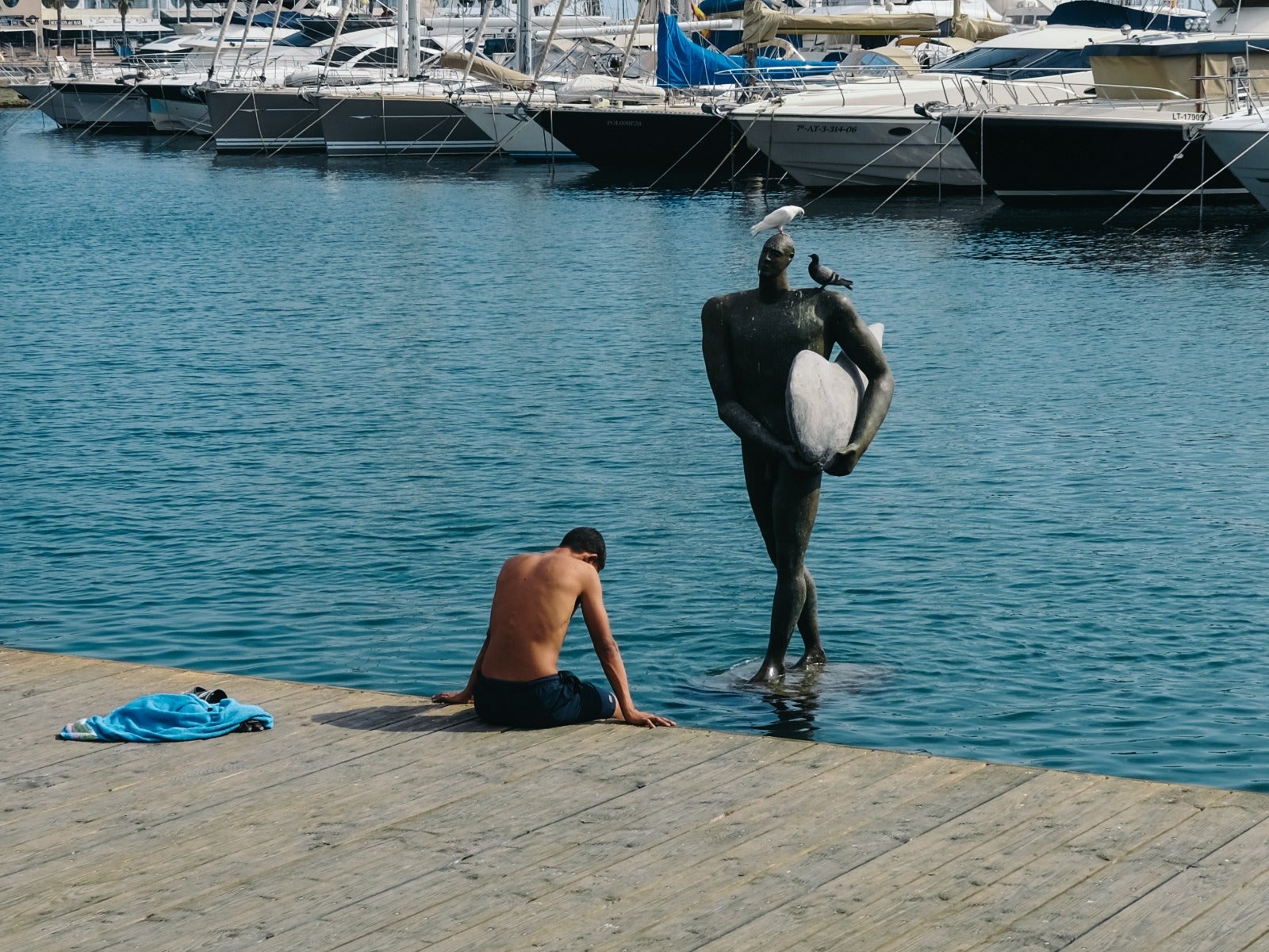 Una persona junto al Puerto de Alicante se refresca en el agua.