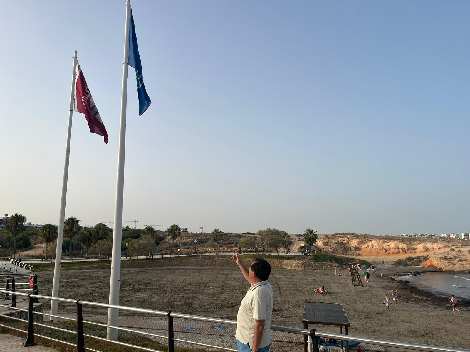 El concejal Manuel Mestre señala la bandera que ha vuelto a ondear en Cala Mosca.