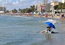 Una persona se refresca en la playa del Postiguet