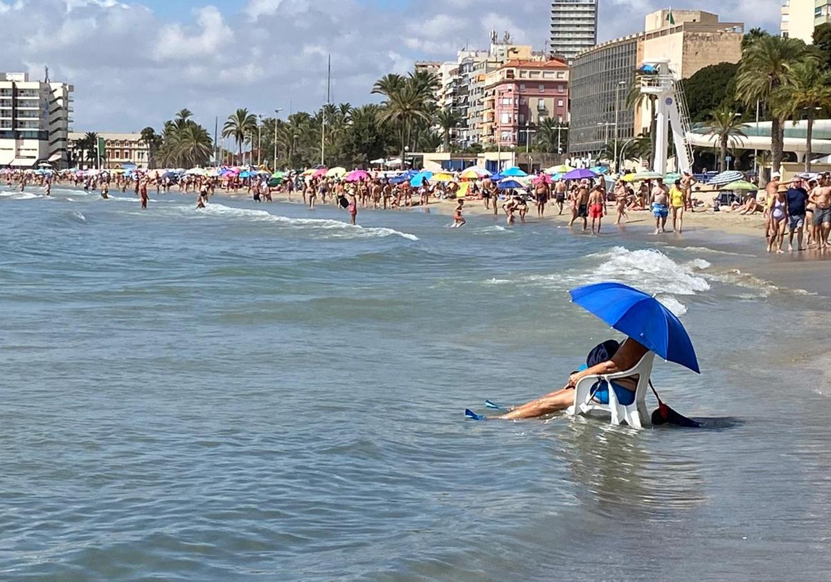 Una persona se refresca en la playa del Postiguet