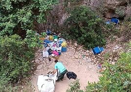 Uno de los encargados de la recogida frente a decenas de bolsas de basura en la cala dels Testos