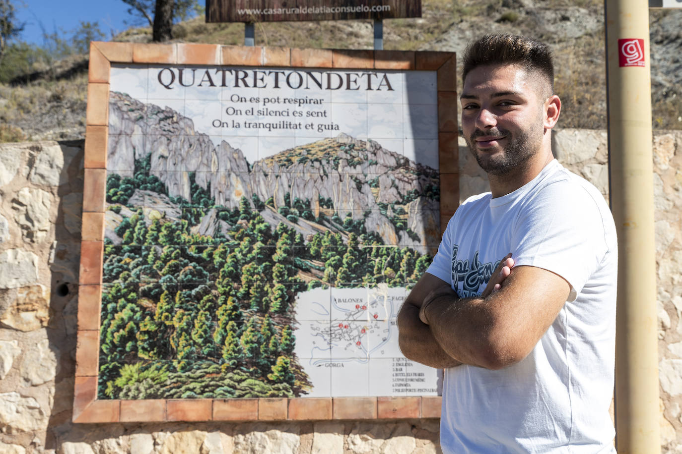 El joven alcalde posa ante el mural que hay a la entrada del pueblo.