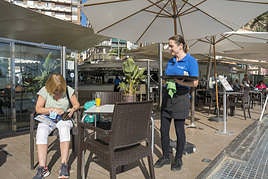 Una camarera trabaja en una terraza de la playa del Postiguet