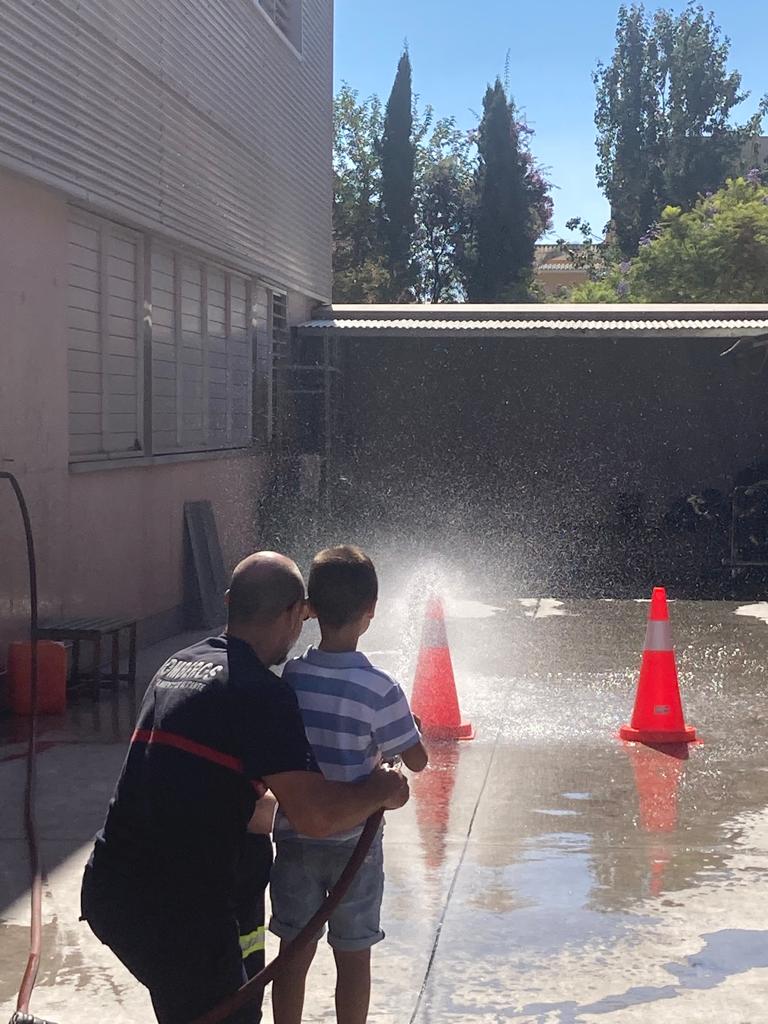 Un bombero y un niño juegan con una manguera.