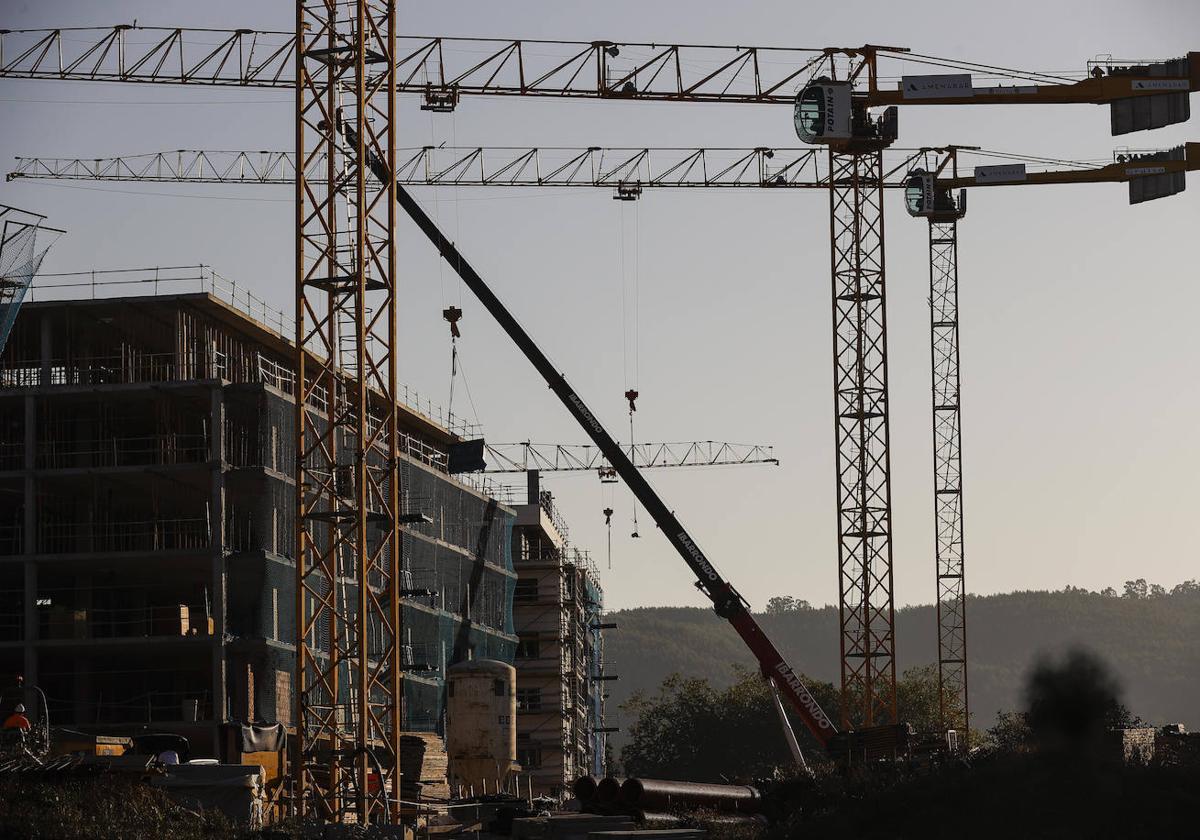 Varias grúas se levantan sobre un edificio en construcción.