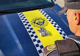 Un agente de la Policía Local de Elche con las 20 bellotas de hachís intervenidas.