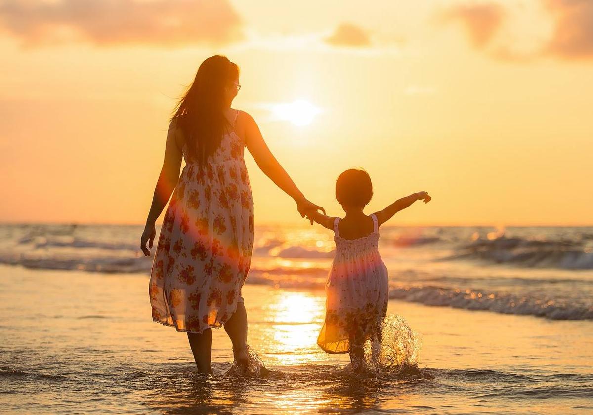 Una madre juega en la playa con su hija.