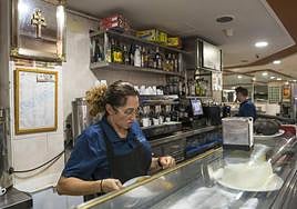 Una camarera atiende en una barra de un bar.