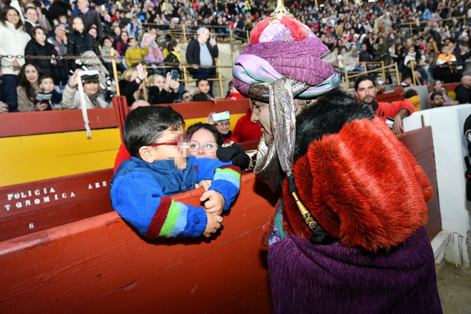 El Rey Baltasar saluda a un niño en el tendido de la plaza de Toros