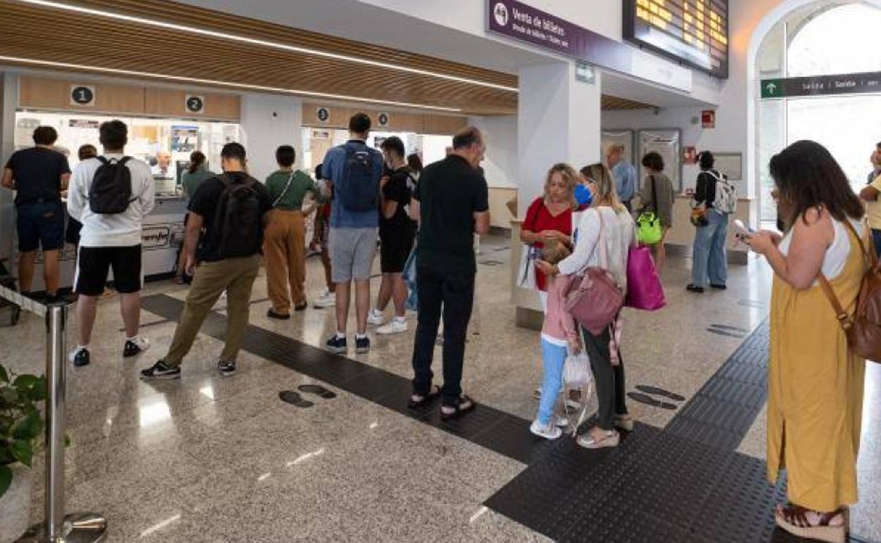 Varias personas hacen cola para adquirir un abono gratuito en la estación de trenes.