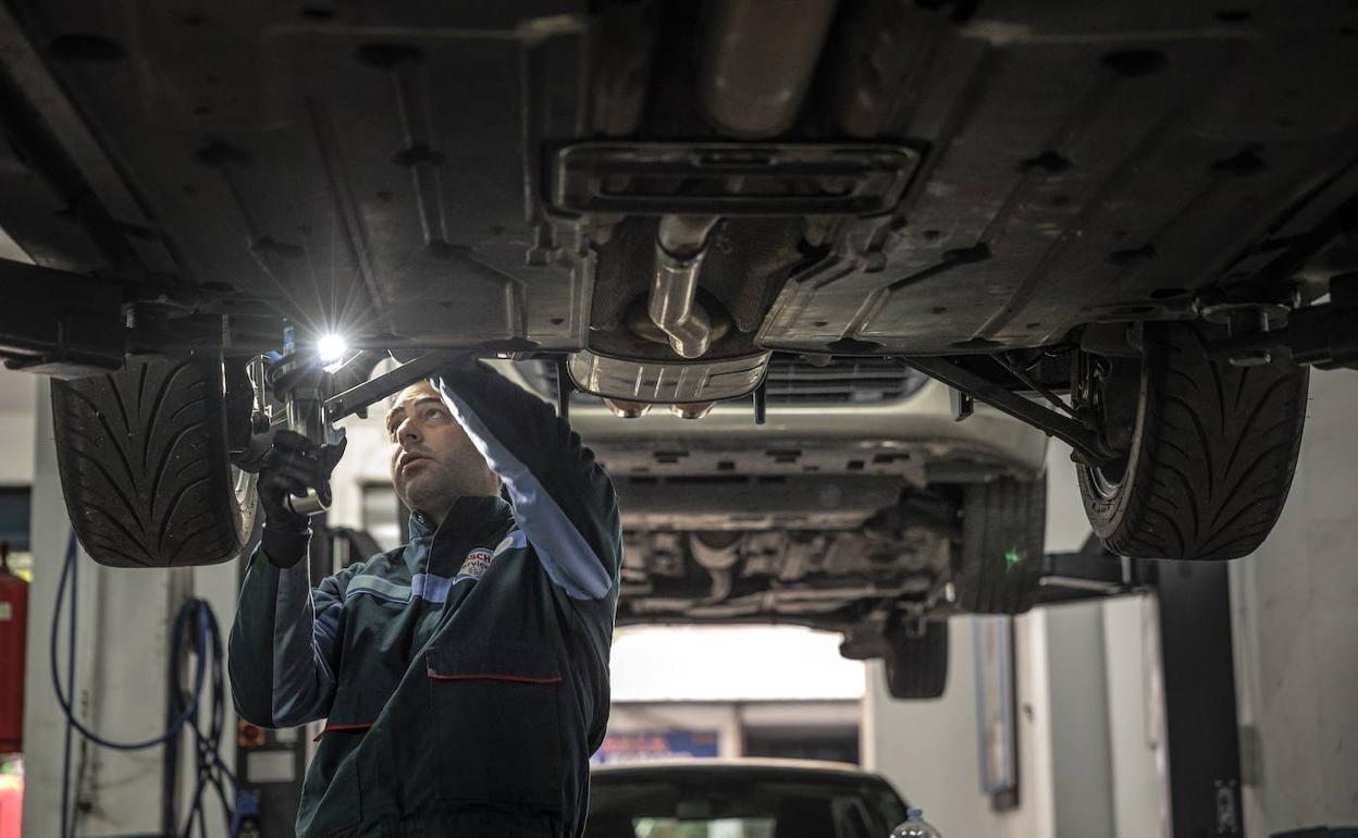 Un mecánico revisa los bajos de un coche 