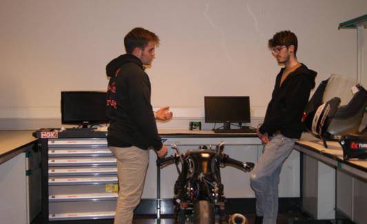 Dos estudiantes de la UMH y miembros del equipo con el prototipo de moto 