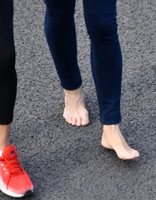 Imagen secundaria 2 - Varios peregrinos caminan descalzos sobre el asfalto.