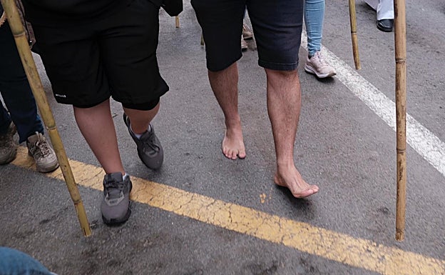 Imagen principal - Varios peregrinos caminan descalzos sobre el asfalto.